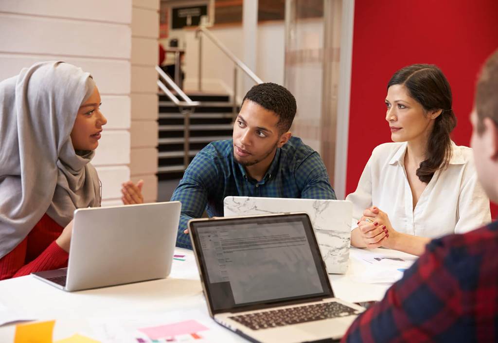 people talking at a table with laptops